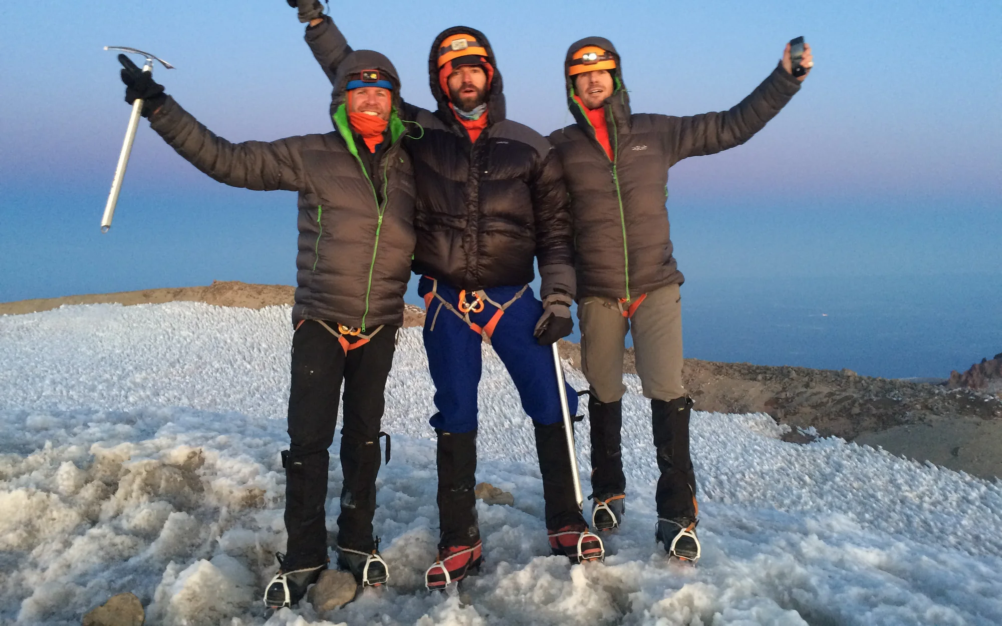 Three climbers celebrating together on a snowy summit